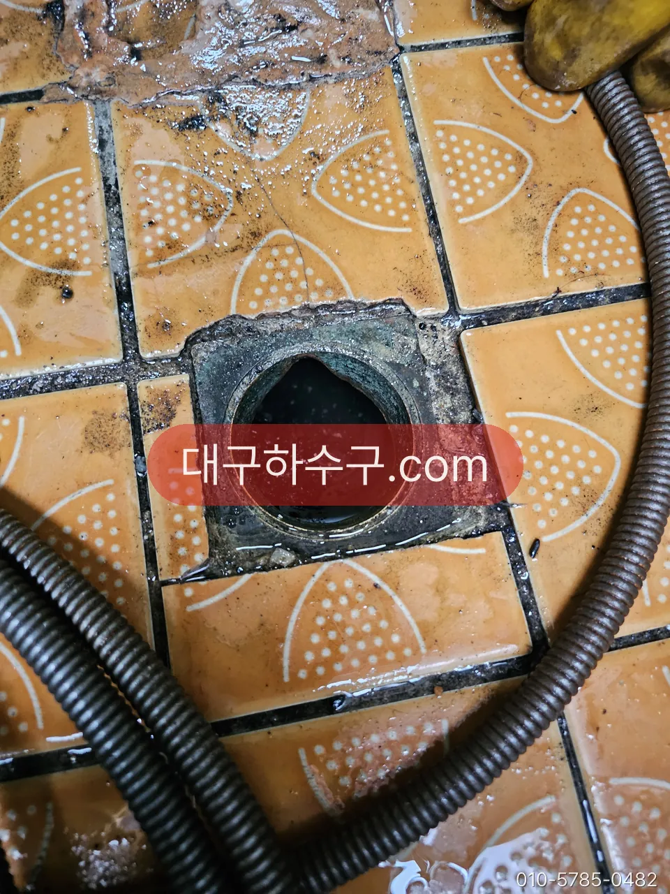 주방 바닥 배수구에 세척 호스를 넣은 모습